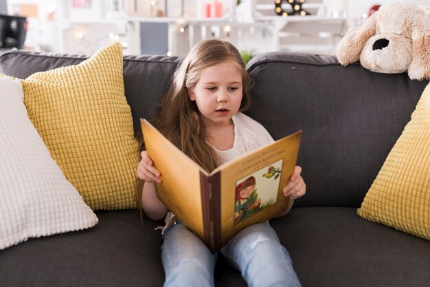 Girl reading book on couch