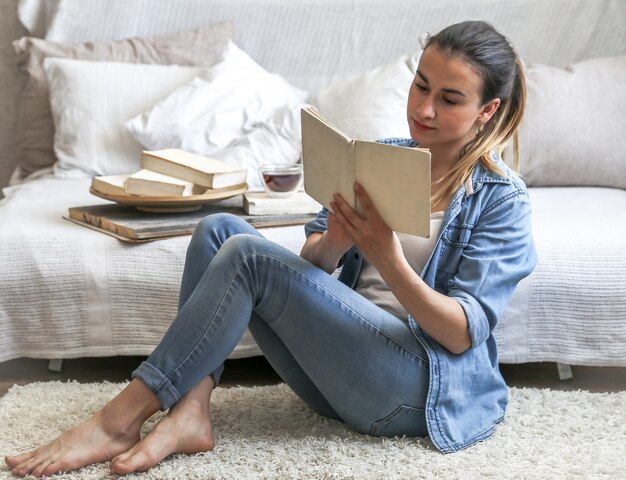 girl reading a book in a cozy room on the couch with a Cup of tea ,the concept of leisure, and comfort