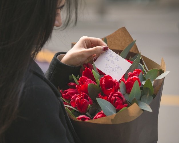 Girl reading a note put into a bouquet of red tulips