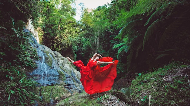 Free Photo girl in a red dress dancing in a waterfall. 