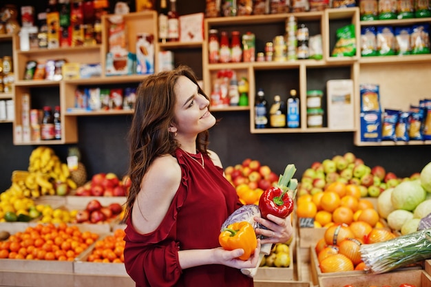 Free Photo girl in red holding different vegetables on fruits store