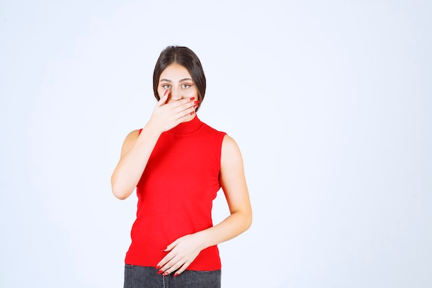 Girl in red shirt pointing at her mouth and asking for silence.