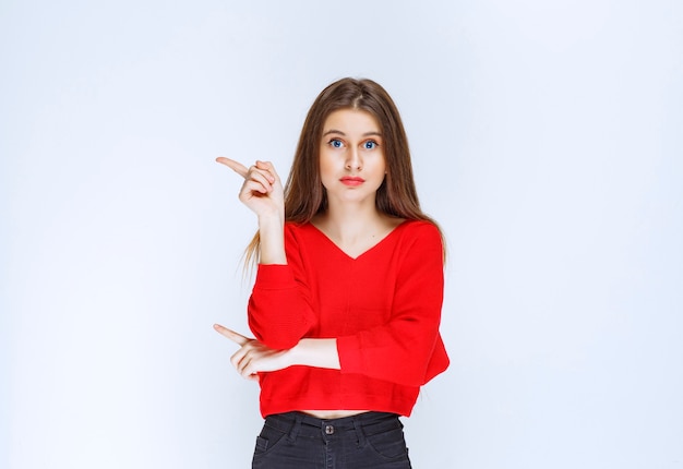 Girl in red shirt pointing to the left side. 