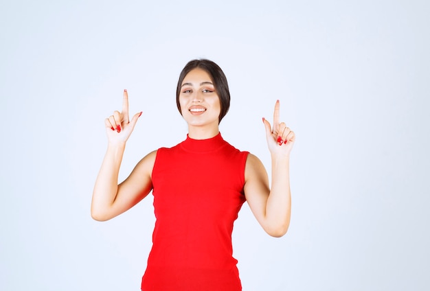 Girl in a red shirt pointing at upside.