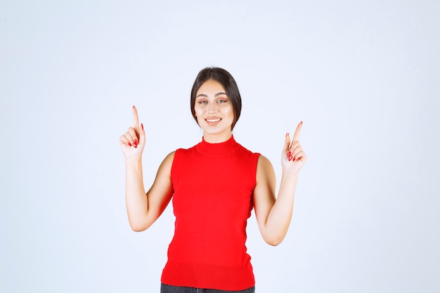 Free Photo girl in red shirt raising hand and pointing above.