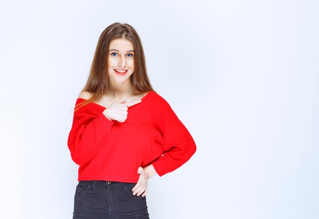 Girl in red shirt showing herself and smiling. 