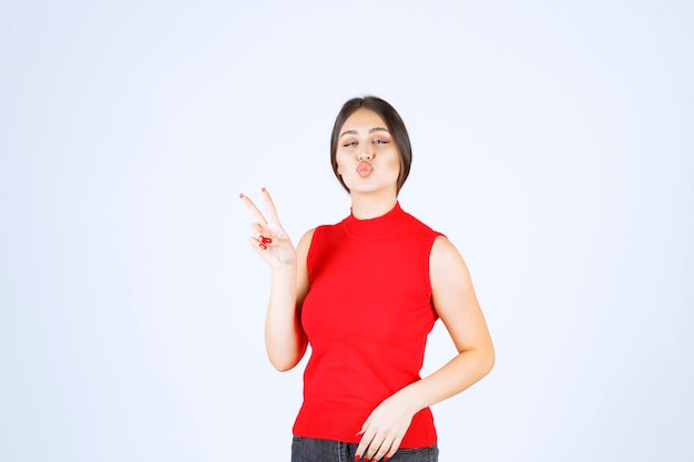 Girl in red shirt showing peace and friendship sign.