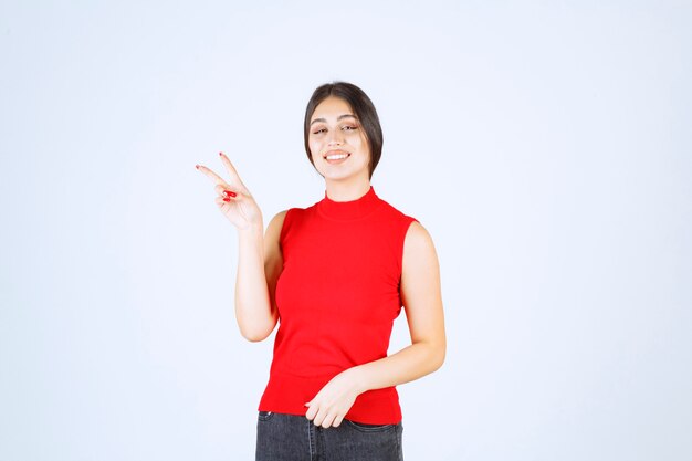 Girl in red shirt showing peace and friendship sign.