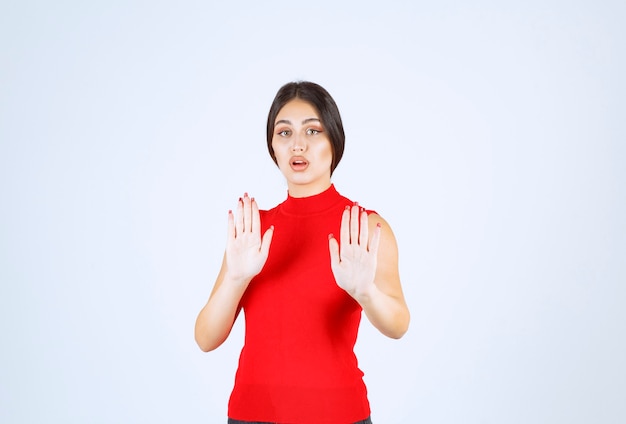 Girl in a red shirt stopping something with hands.