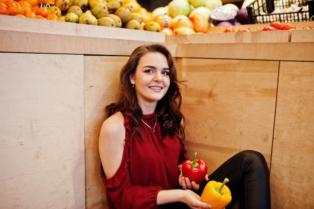 Girl in red throw peppers on fruits store