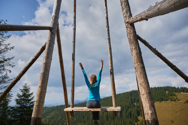 Girl relaxing in seat of swing in the mountains