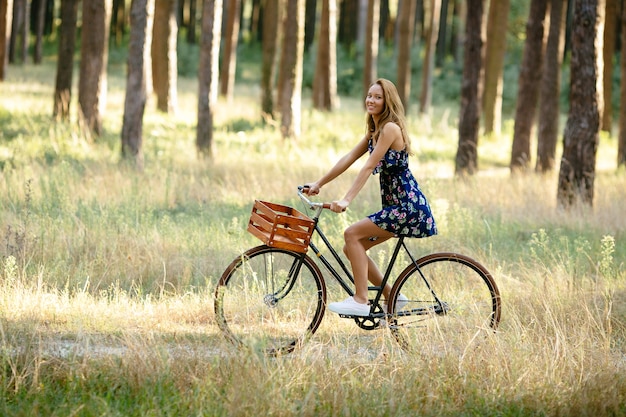 Girl rides a bicycle with a basket in the woods.