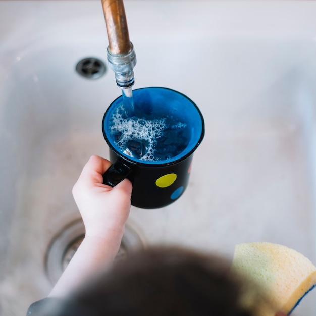 Girl's hand filling cup with water