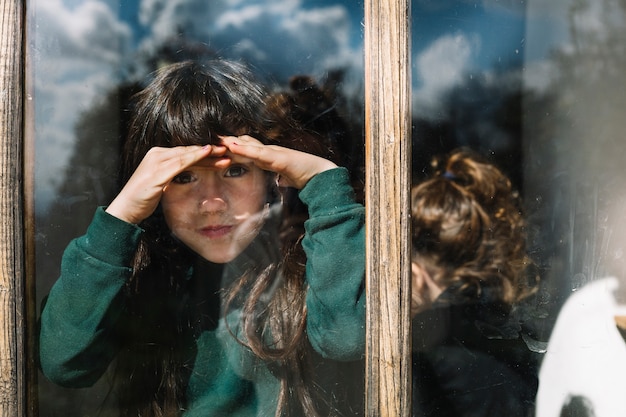 Girl shielding her eyes while looking through glass window