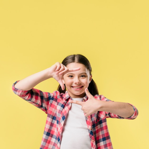 Girl showing finger frame in studio