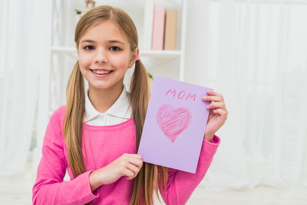 Free photo girl showing greeting card with mom inscription