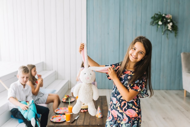 Free photo girl showing toy bunny on birthday party