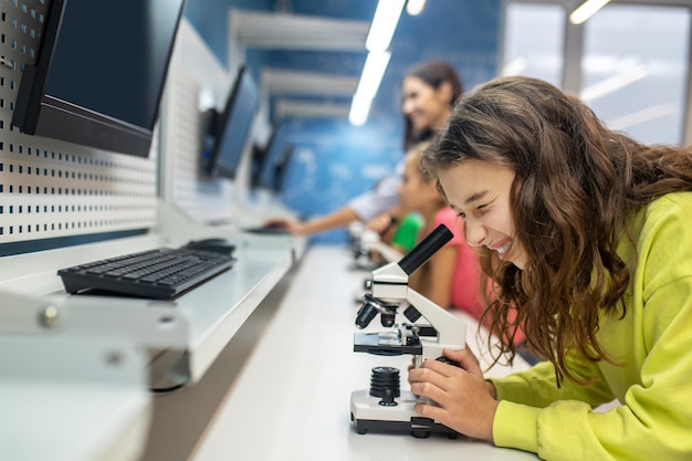 Free photo girl sideways to camera looking into microscope with interest