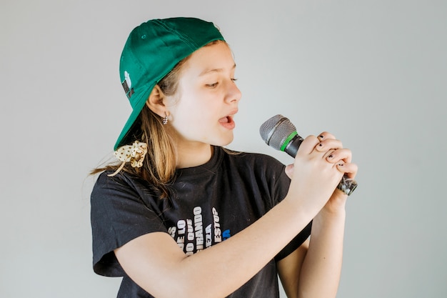 Girl singing song with microphone on grey background