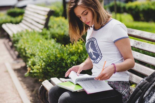 Free photo girl sitting on bench holding notebooks studying