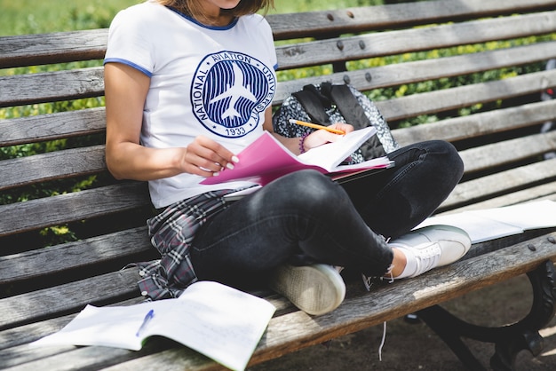 Free photo girl sitting on bench in park studying