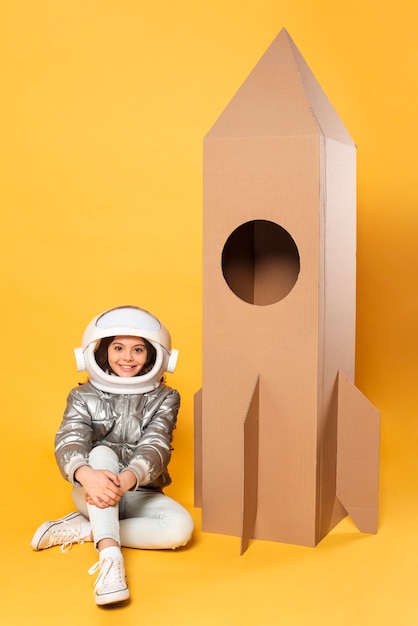 Free Photo girl sitting beside space ship cartoon toy