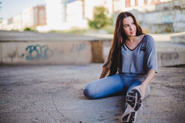 Girl sitting on concrete floor stretching