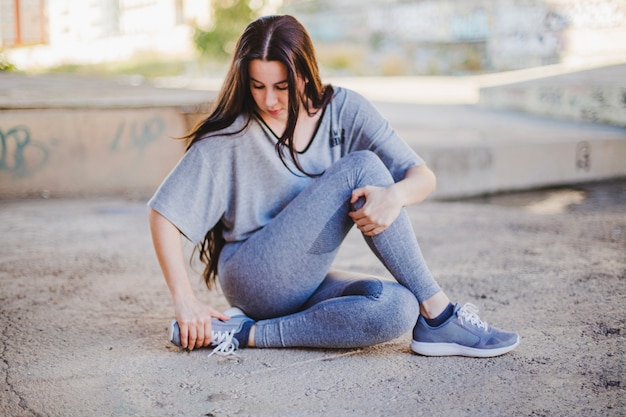 Girl sitting on concrete floor stretching