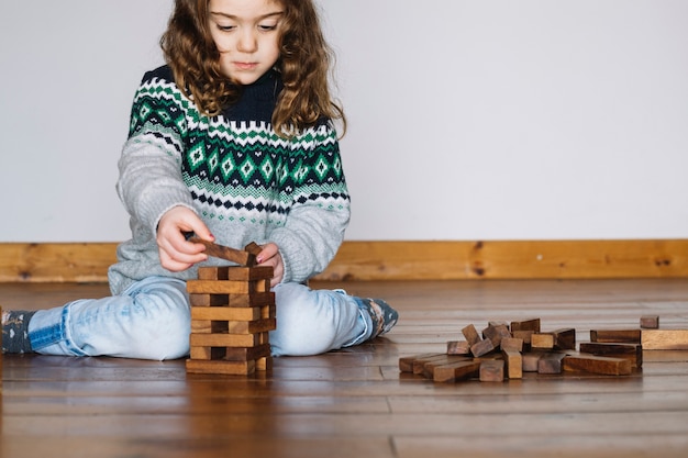 Free photo girl sitting on floor playing jenga game