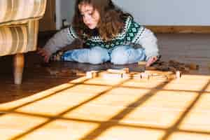 Free photo girl sitting on floor playing with wooden blocks