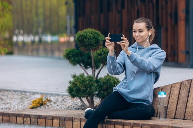 Girl sitting on leg on bench taking selfie