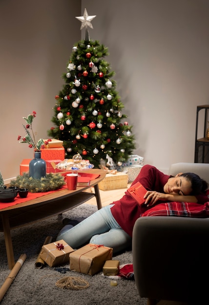 Free photo girl sitting in a red jumper with a christmas background