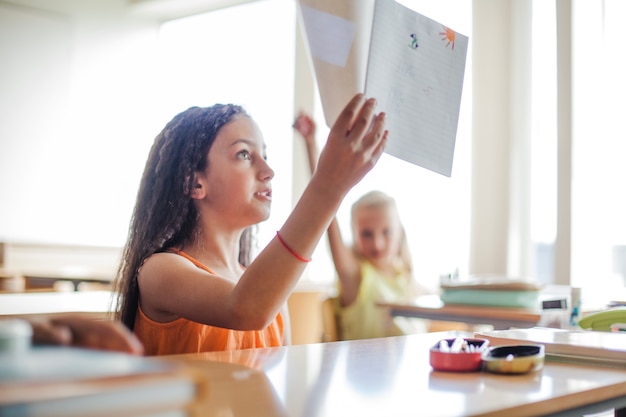 Girl sitting at school desk holding notebook