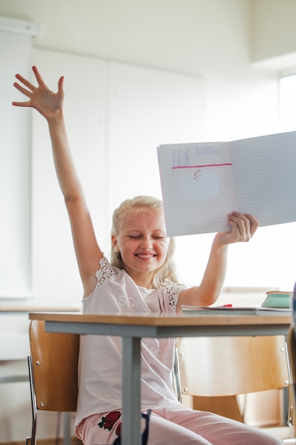 Free photo girl sitting at school table with notebook