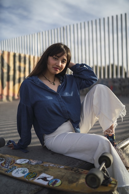 Free photo girl sitting next to a skateboard in a skate park