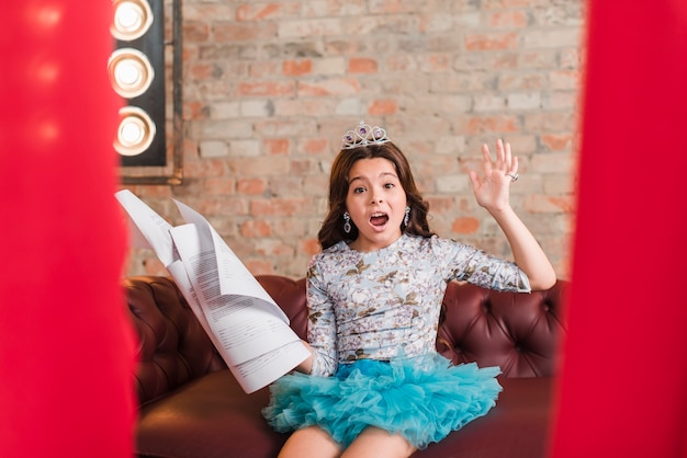 Free photo girl sitting on sofa holding scripts rehearsing