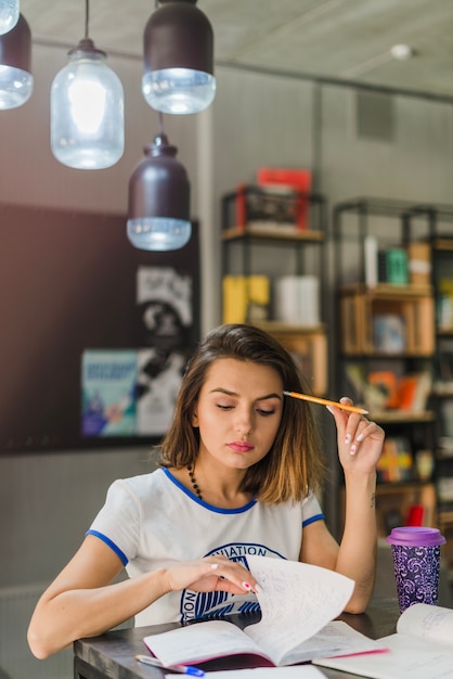 Free Photo girl sitting at table holding pencil