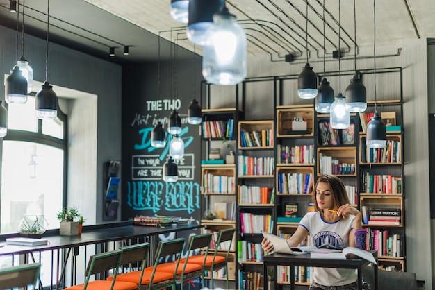 Free photo girl sitting at table looking at notebook