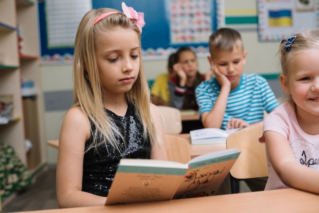 Free Photo girl sitting at table reading book