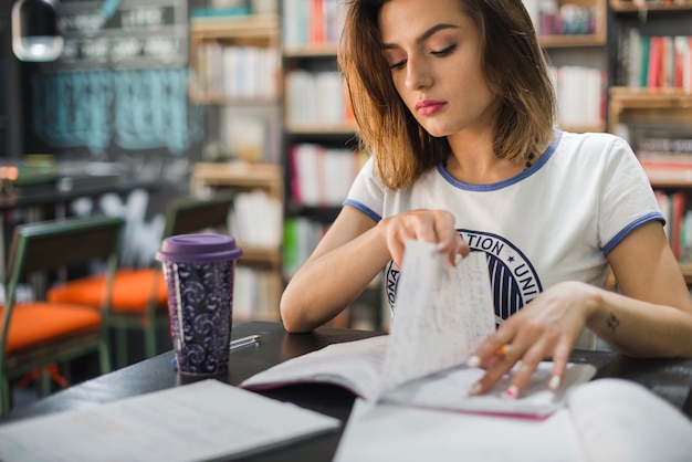 Girl sitting at table reading flipping page