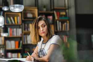 Free photo girl sitting at table with notebooks writing