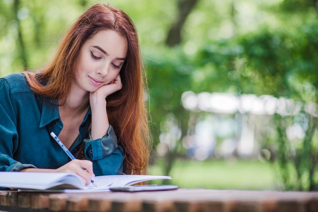 Free Photo girl sitting at table writing