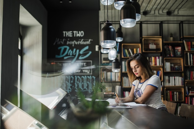 Free photo girl sitting at table writing