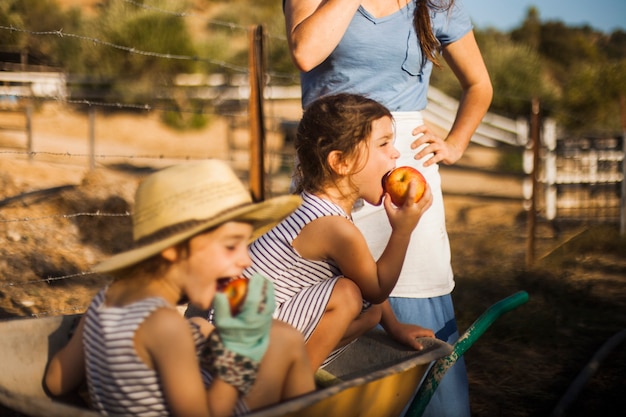 Free Photo girl sitting in the wheel borrow eating apple