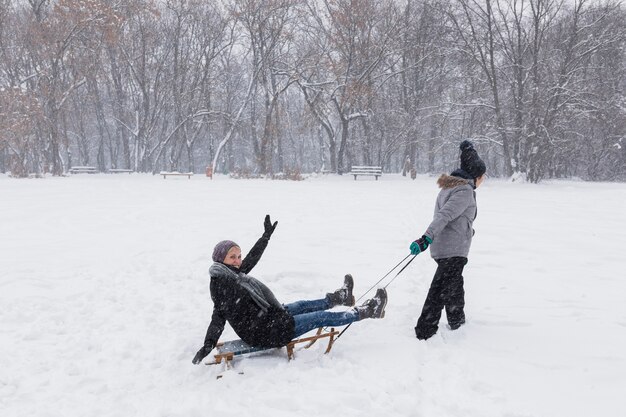 Girl sledding her mother at winter park