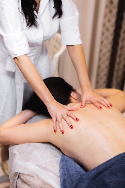 The girl in the spa salon receives a back and neck massage, lies in the cosmetology table, relaxed and enjoys the process