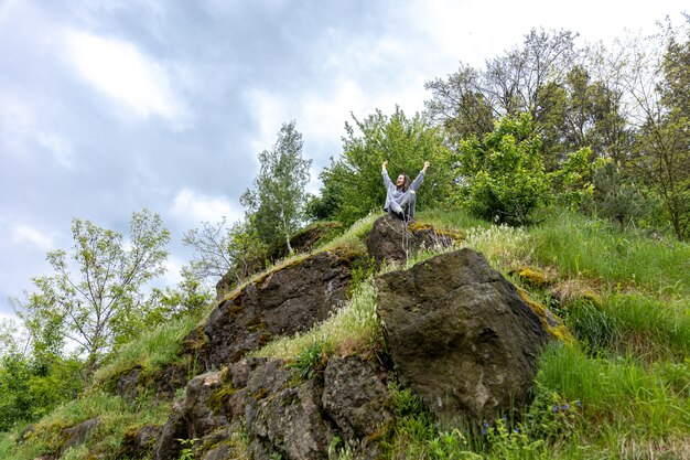 A girl in the spring forest sits on a stone among the greenery.