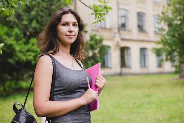 Girl standing holding notebook pencil smiling