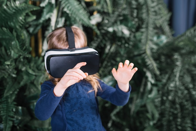 Free Photo girl standing near the plants wearing virtual reality glasses touching the hands in air