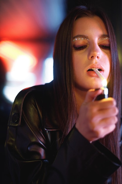 Girl standing in a night club with colorful bright neon red lights and smoking